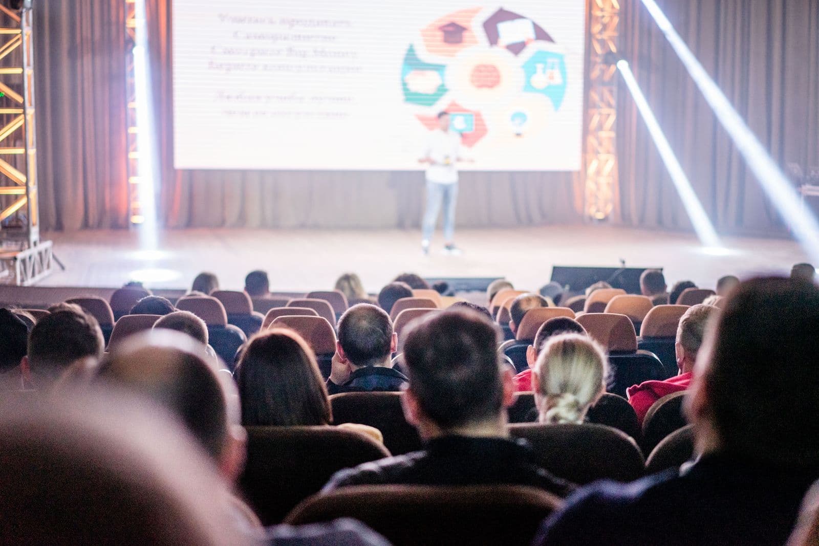 Rows of seated attendees in a dark corporate conference auditorium